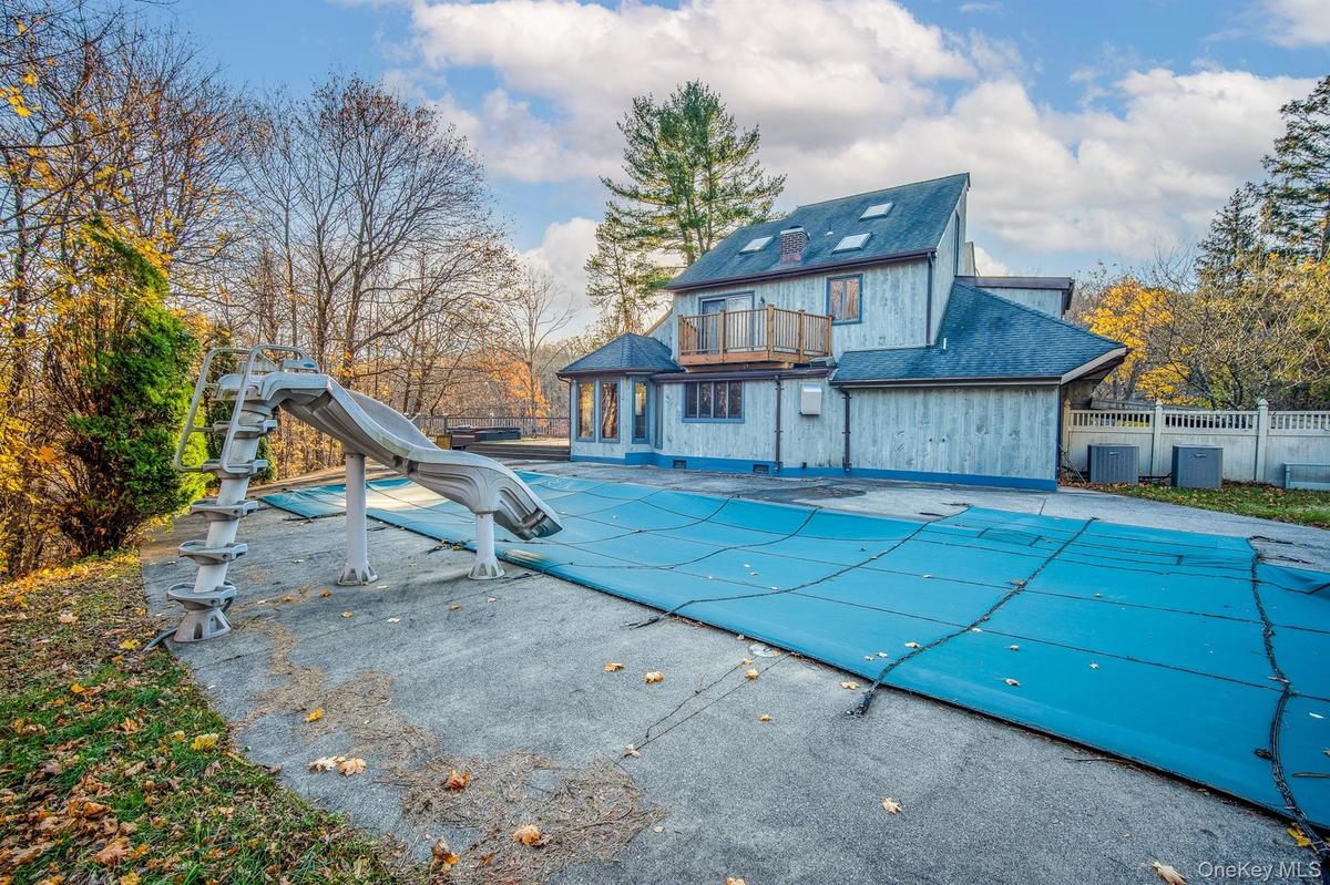 View of pool with a water slide, a balcony, and a patio