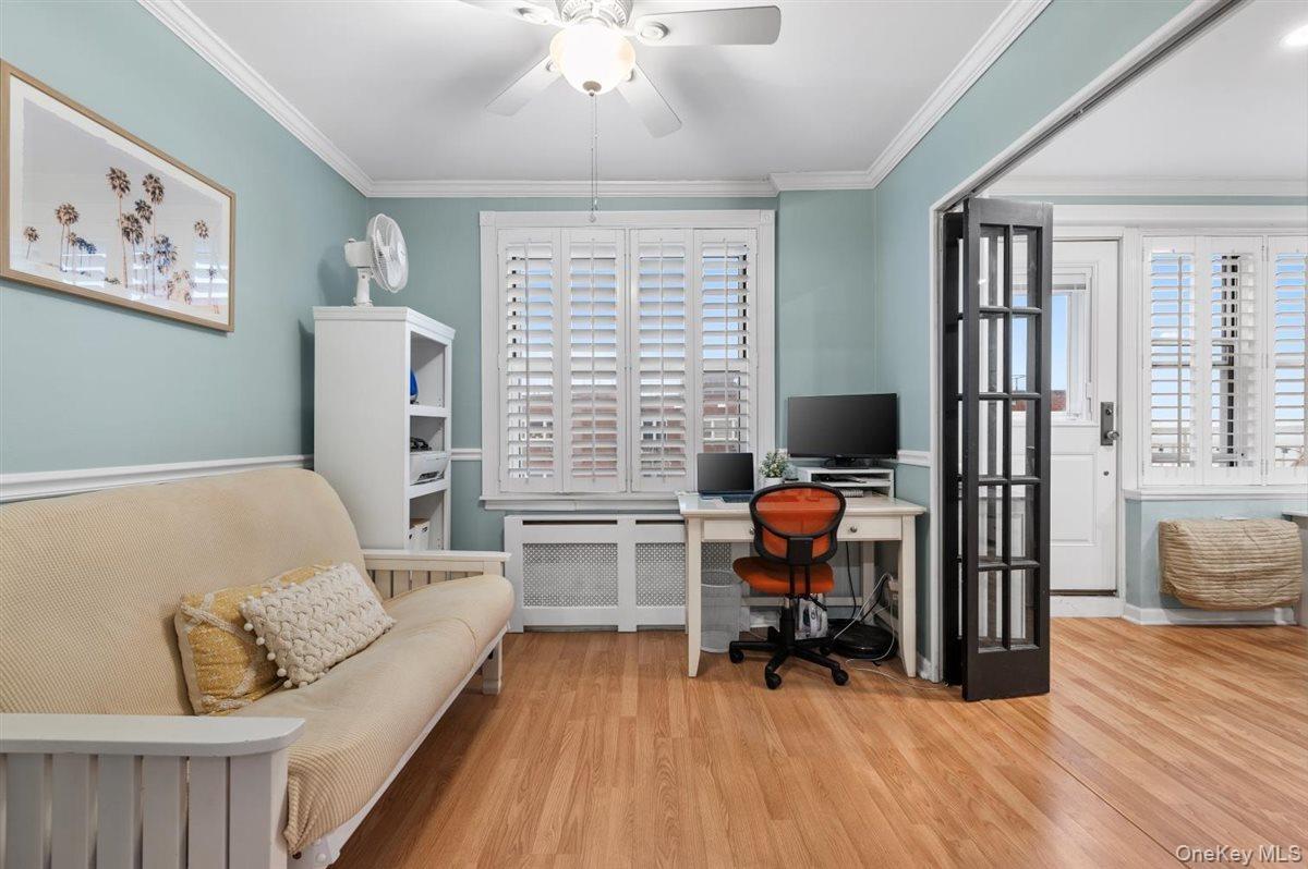 Office with radiator heating unit, a ceiling fan, wood finished floors, and ornamental molding