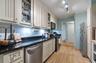 Kitchen featuring appliances with stainless steel finishes, glass insert cabinets, dark stone counters, decorative backsplash, and crown molding
