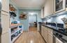 Kitchen featuring cream cabinetry, a desk, light wood-type flooring, dark stone counters, and glass insert cabinets