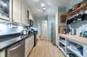 Kitchen featuring appliances with stainless steel finishes, cream cabinetry, light wood-type flooring, dark stone counters, and glass insert cabinets