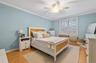 Bedroom with ornamental molding, a ceiling fan, and light wood-style flooring