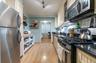 Kitchen with appliances with stainless steel finishes, light wood finished floors, open shelves, ornamental molding, and rail lighting