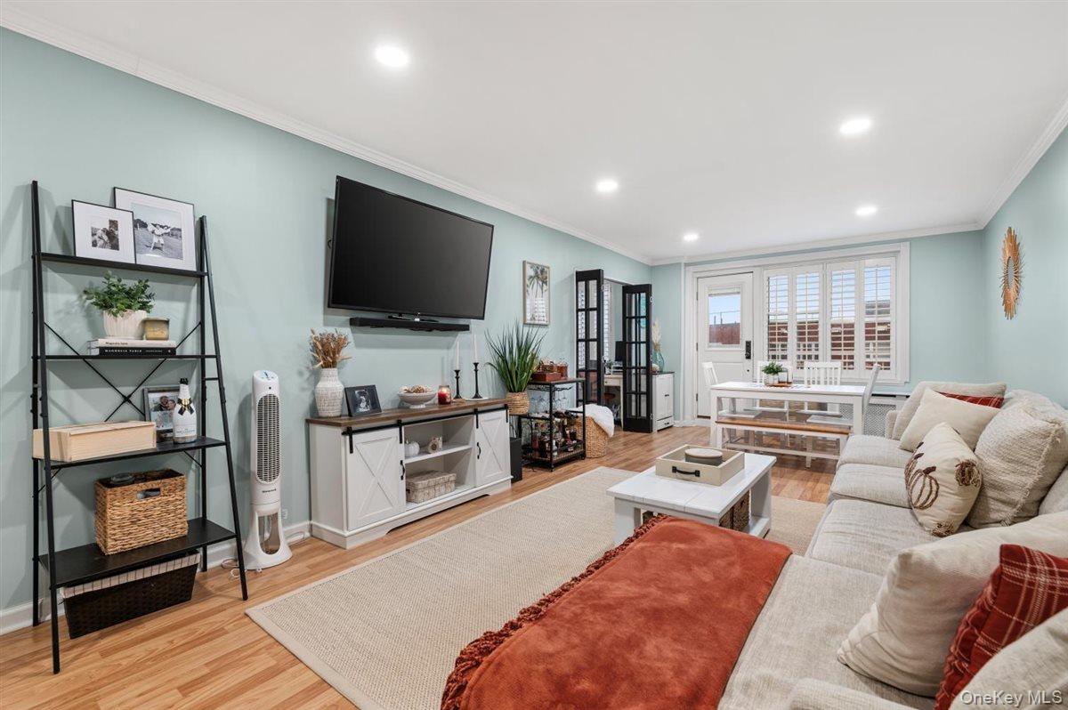 Living room with light wood finished floors, recessed lighting, and crown molding
