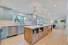 Kitchen featuring decorative light fixtures, open shelves, a kitchen island, light wood-style flooring, and a kitchen breakfast bar