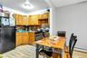 Kitchen with freestanding refrigerator, backsplash, brown cabinetry, a baseboard radiator, and light stone counters