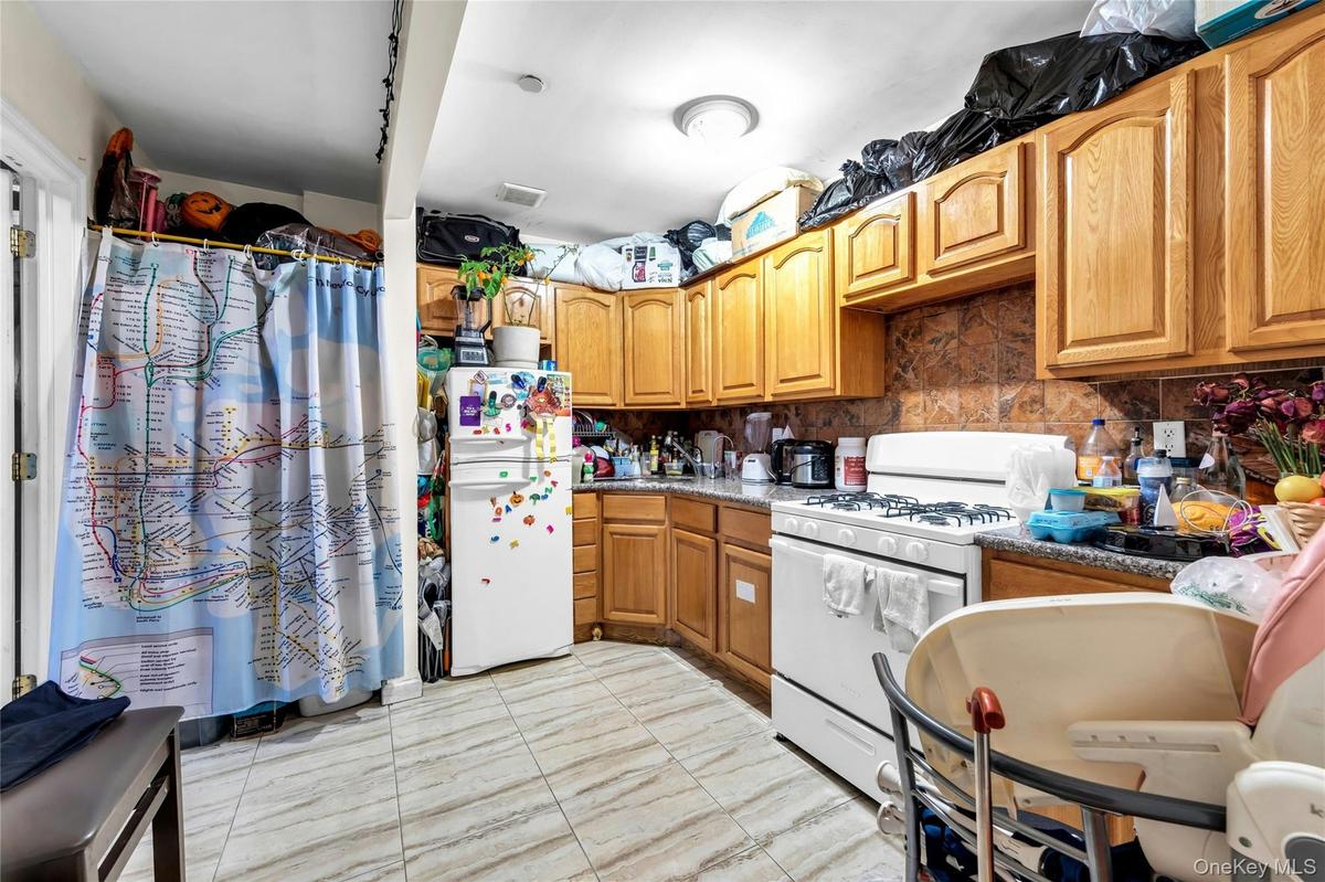 Kitchen with white appliances, decorative backsplash, brown cabinets, and light marble finish floors