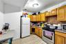 Kitchen with stainless steel appliances, brown cabinets, backsplash, and light marble finish floors