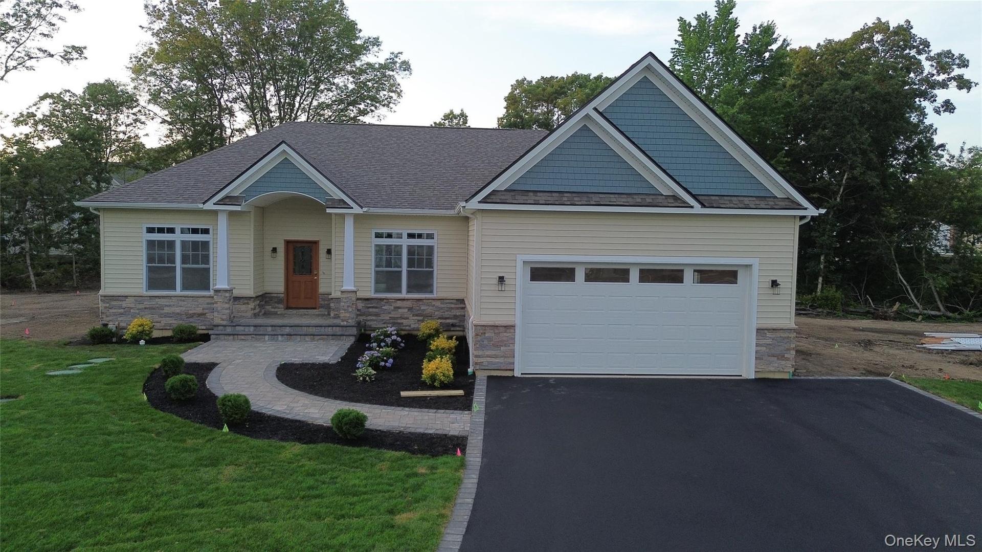 Craftsman house with asphalt driveway, stone siding, a front lawn, a shingled roof, and a garage