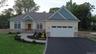 Craftsman house with asphalt driveway, stone siding, a front lawn, a shingled roof, and a garage
