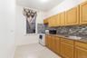 Kitchen featuring white range with gas stovetop, black microwave, tasteful backsplash, and light tile patterned floors