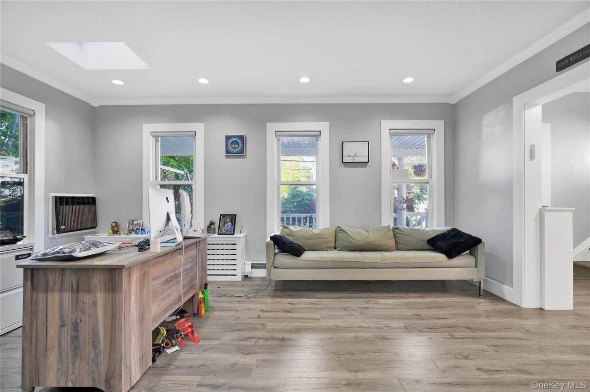 Office space featuring light wood-style floors, crown molding, recessed lighting, a skylight, and baseboard heating