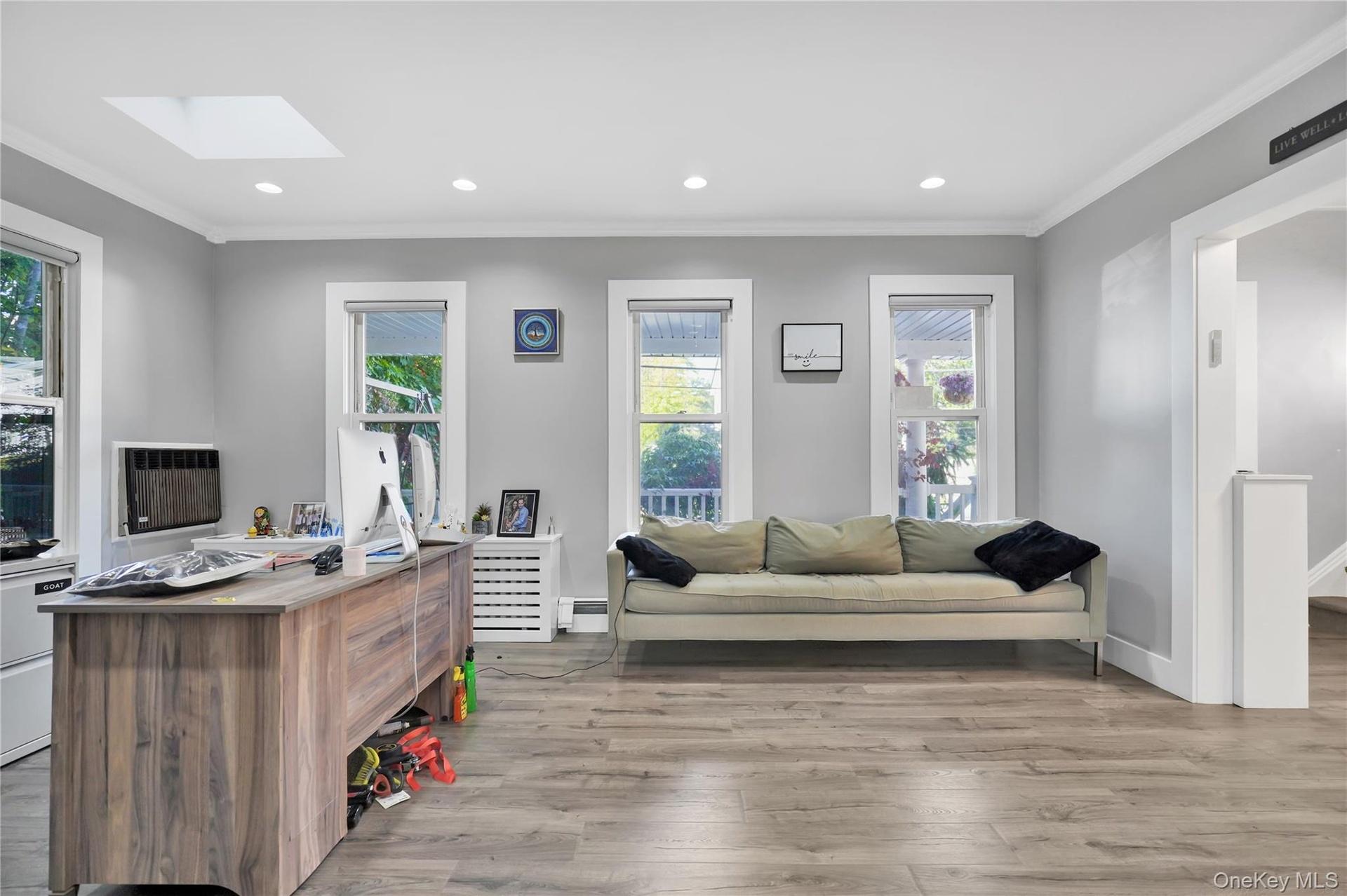 Office space featuring light wood-style floors, crown molding, recessed lighting, a skylight, and baseboard heating