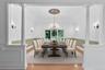 Virtually Staged Dining area featuring decorative columns, wainscoting, wood-type flooring, a chandelier, and a decorative wall