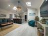 Living room featuring a skylight, light wood-style flooring, high vaulted ceiling, an AC wall unit, and recessed lighting