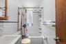 Full bath with tile walls, shower / tub combo with curtain, vanity, and wainscoting