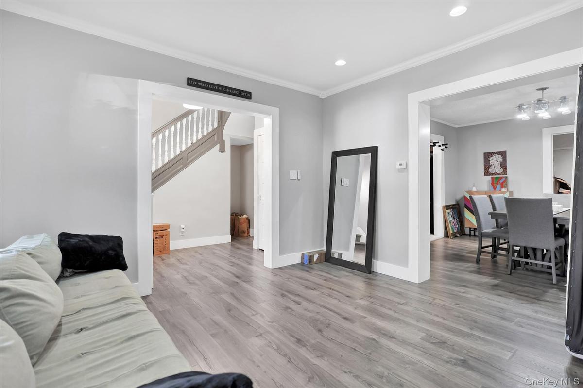 Living area with ornamental molding, light wood-style floors, stairway, and recessed lighting