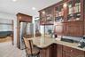 Kitchen featuring freestanding refrigerator, a kitchen bar, light stone counters, a peninsula, and recessed lighting