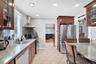 Kitchen with glass insert cabinets, stainless steel appliances, light stone countertops, wall chimney exhaust hood, and a breakfast bar area