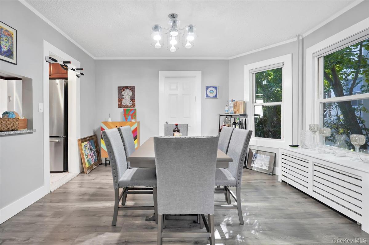 Dining room featuring radiator, crown molding, light wood finished floors, and a chandelier
