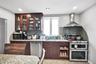 Kitchen featuring stainless steel appliances, wall chimney exhaust hood, glass insert cabinets, backsplash, and recessed lighting