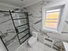 Bathroom with light marble finish floors, a marble finish shower, ornamental molding, tile walls, and radiator