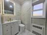 Full bath with tile walls, light marble finish floors, vanity, radiator heating unit, and a marble finish shower
