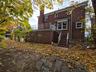 Back of house featuring a chimney, a wooden deck, brick siding, and stairs