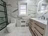 Bathroom with vanity, radiator heating unit, and light marble finish flooring