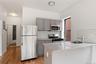 Kitchen featuring gray cabinets, light stone countertops, stainless steel appliances, a peninsula, and backsplash