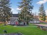 View of front of home featuring stone siding, a front yard, and a chimney