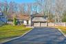 Split level home with stone siding, asphalt driveway, a garage, and a gate