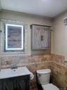 Bathroom with vanity, wainscoting, tile walls, and crown molding