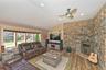 Living area with vaulted ceiling, a warm lit fireplace, hardwood / wood-style floors, a ceiling fan, and recessed lighting