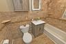 Bathroom with vanity,  shower combination, tile walls, and a baseboard heating unit