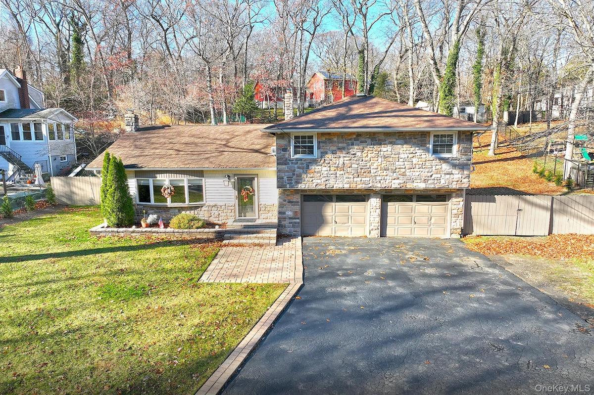 Tri-level home with stone siding, driveway, and a garage