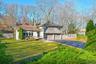Split level home with stone siding, asphalt driveway, a chimney, and an attached garage
