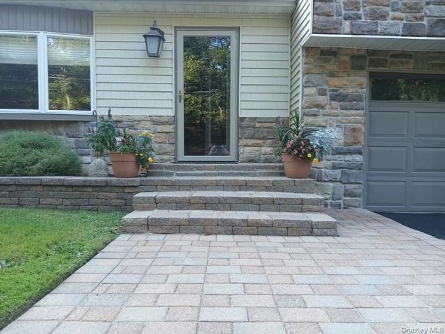 Property entrance featuring stone siding and a garage