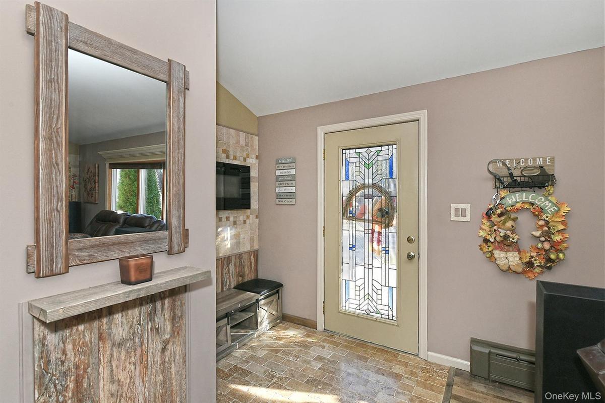 Entryway with baseboard heating, brick flooring, healthy amount of natural light, and lofted ceiling