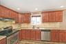 Kitchen with appliances with stainless steel finishes, backsplash, light stone counters, under cabinet range hood, and recessed lighting