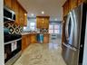 Kitchen featuring appliances with stainless steel finishes, brown cabinets, decorative backsplash, radiator heating unit, and recessed lighting