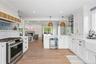 Kitchen with stainless steel gas stove, open shelves, open floor plan, wine cooler, and white cabinetry