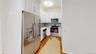 Kitchen with appliances with stainless steel finishes, white cabinetry, light wood finished floors, backsplash, and light stone counters