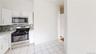 Kitchen with stainless steel appliances, white cabinets, tasteful backsplash, and light stone countertops