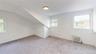 Bonus room featuring plenty of natural light, radiator heating unit, light colored carpet, and lofted ceiling