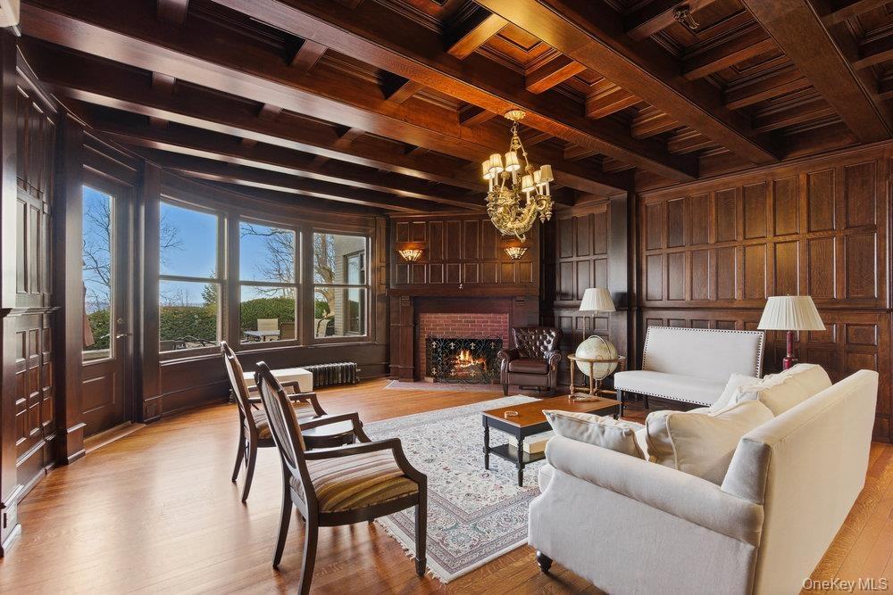 Parlor with a wood ceiling with exposed beams,  chandelier, and brick fireplace, original oak flooring