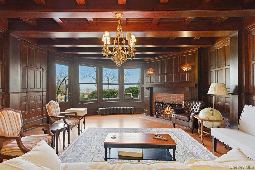 Parlor featuring original oak floors,  a custom mermaid chandelier, and a brick fireplace