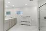 Primary bathroom with double vanity, quartz countertops, ceramic tile shower