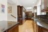 Kitchen with skylight,  stone countertops, hardwood  floors under cabinet range hood, and ornamental molding