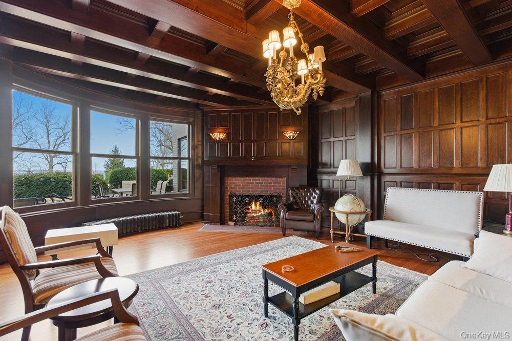 Parlor with wood millwork walls, a wood ceiling with exposed beams, brick fireplace, custom mermaid chandelier, and original oak floors